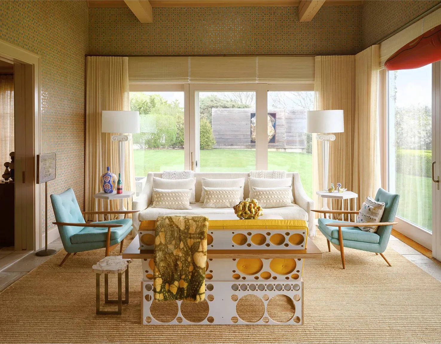 "Here's the sunroom, and it's such a great spot to relax! The big windows really let in all that natural light, and you can see the backyard from here. I love how cheerful those chairs look, too!"