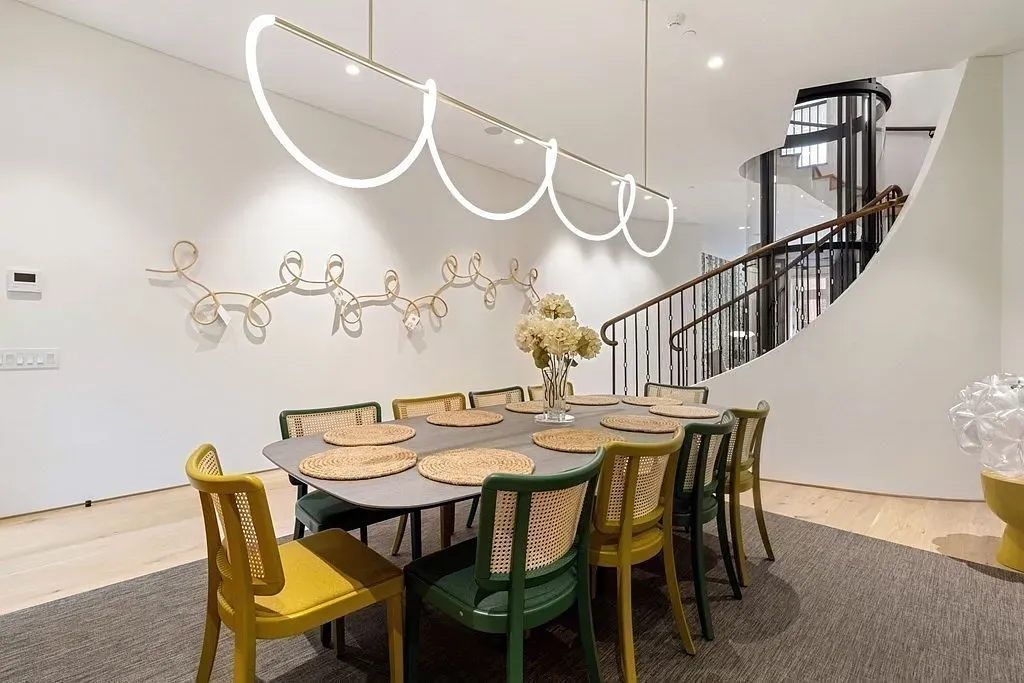 "Here’s the dining area! I love the mix of colors in the chairs—it's such a fun touch. The lighting above is really unique, and the open space flows nicely into the staircase. Perfect for hosting friends or family gatherings!"