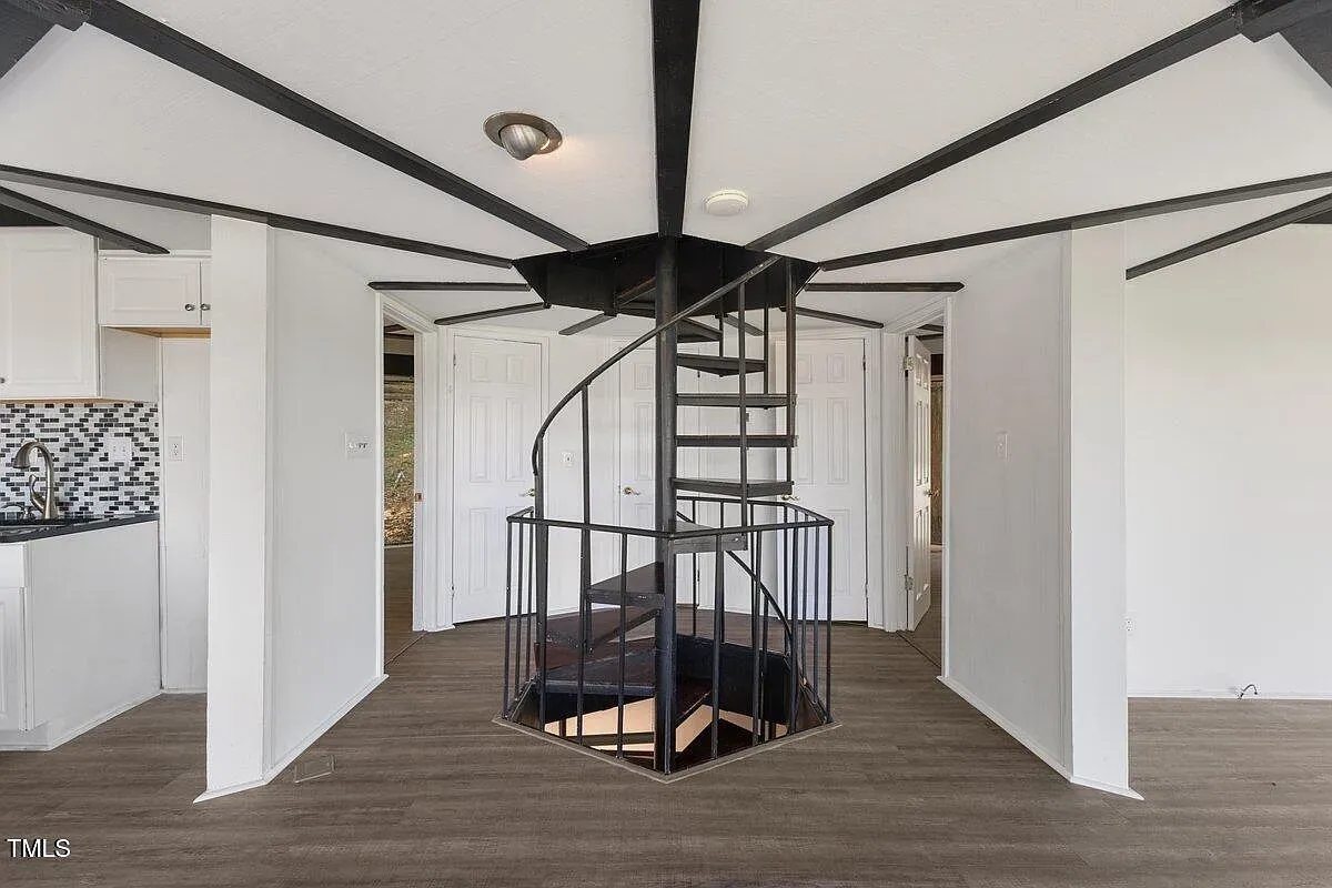 ## A sculptural spiral staircase takes center stage; black steel against pale walls delivers a sharp, modern punch