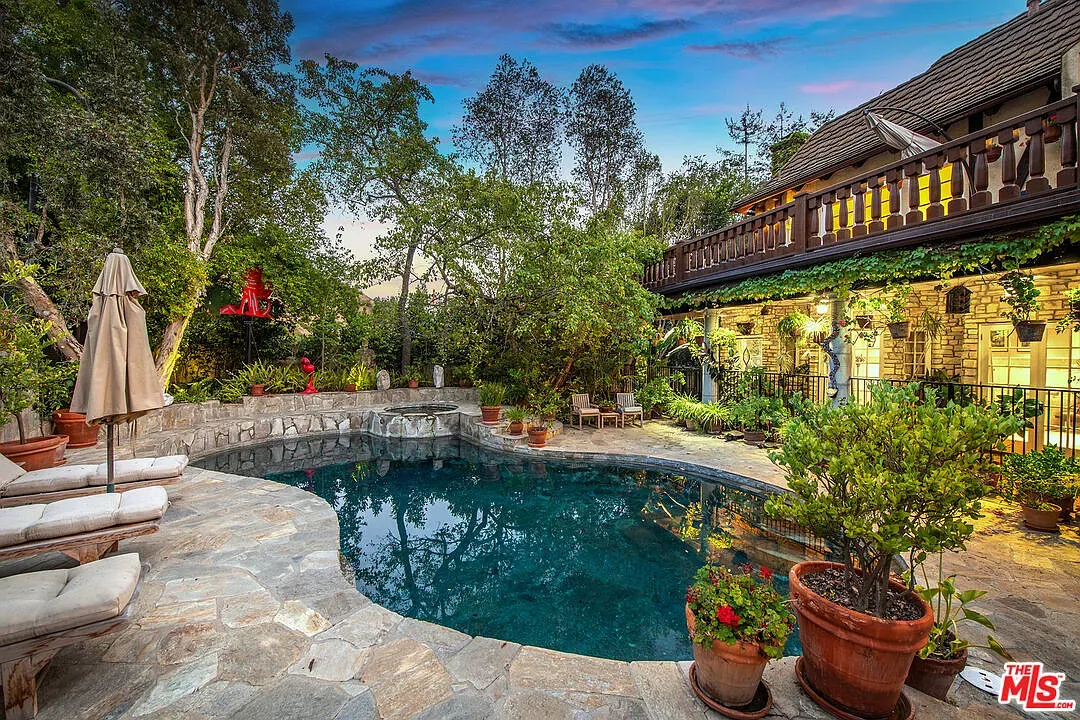Another pool angle—organic shape, rough stone deck, plants wrapping it in.