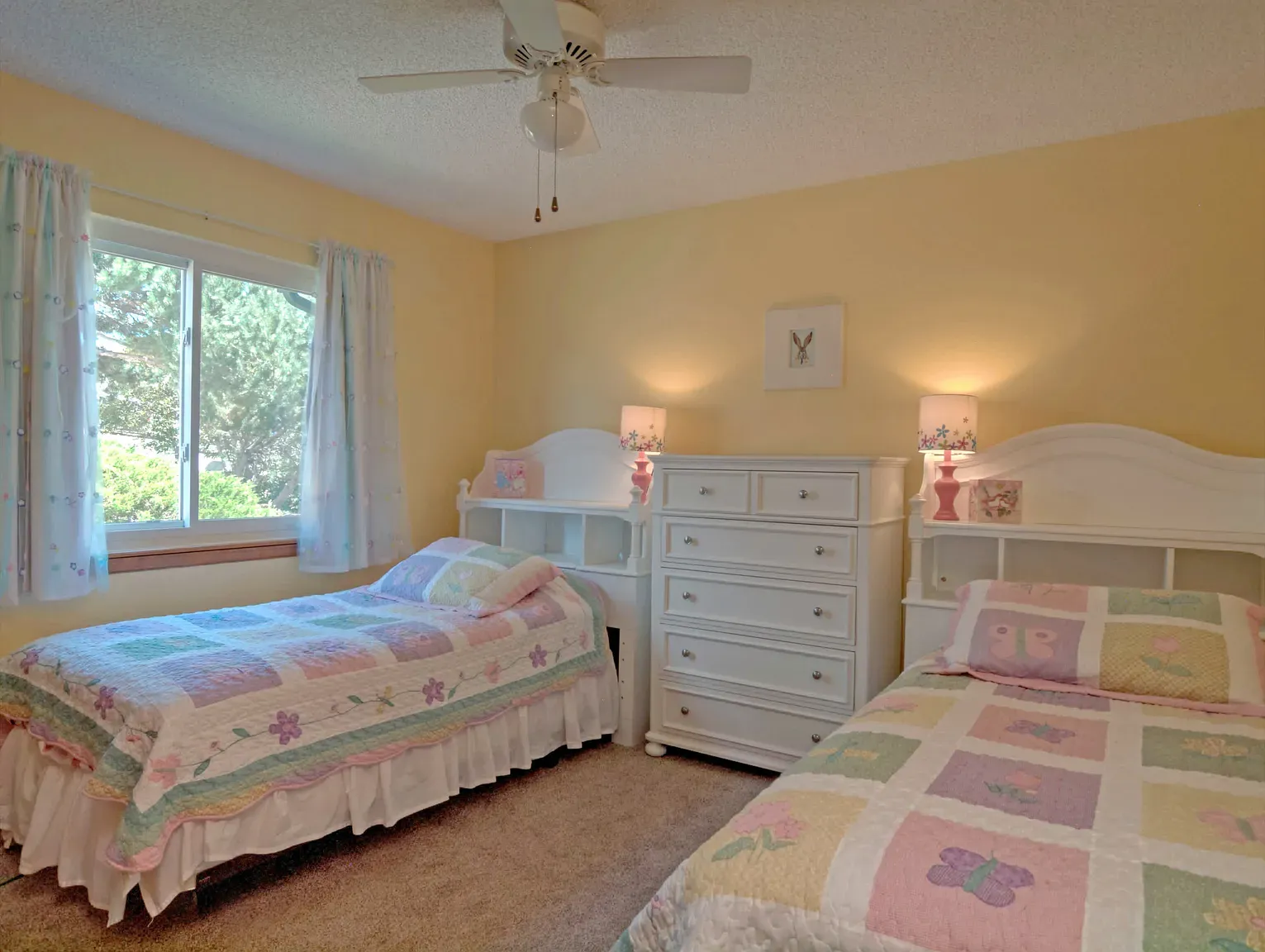 Sunny bedroom with yellow walls and pastel curtains. Kid room? Cute.