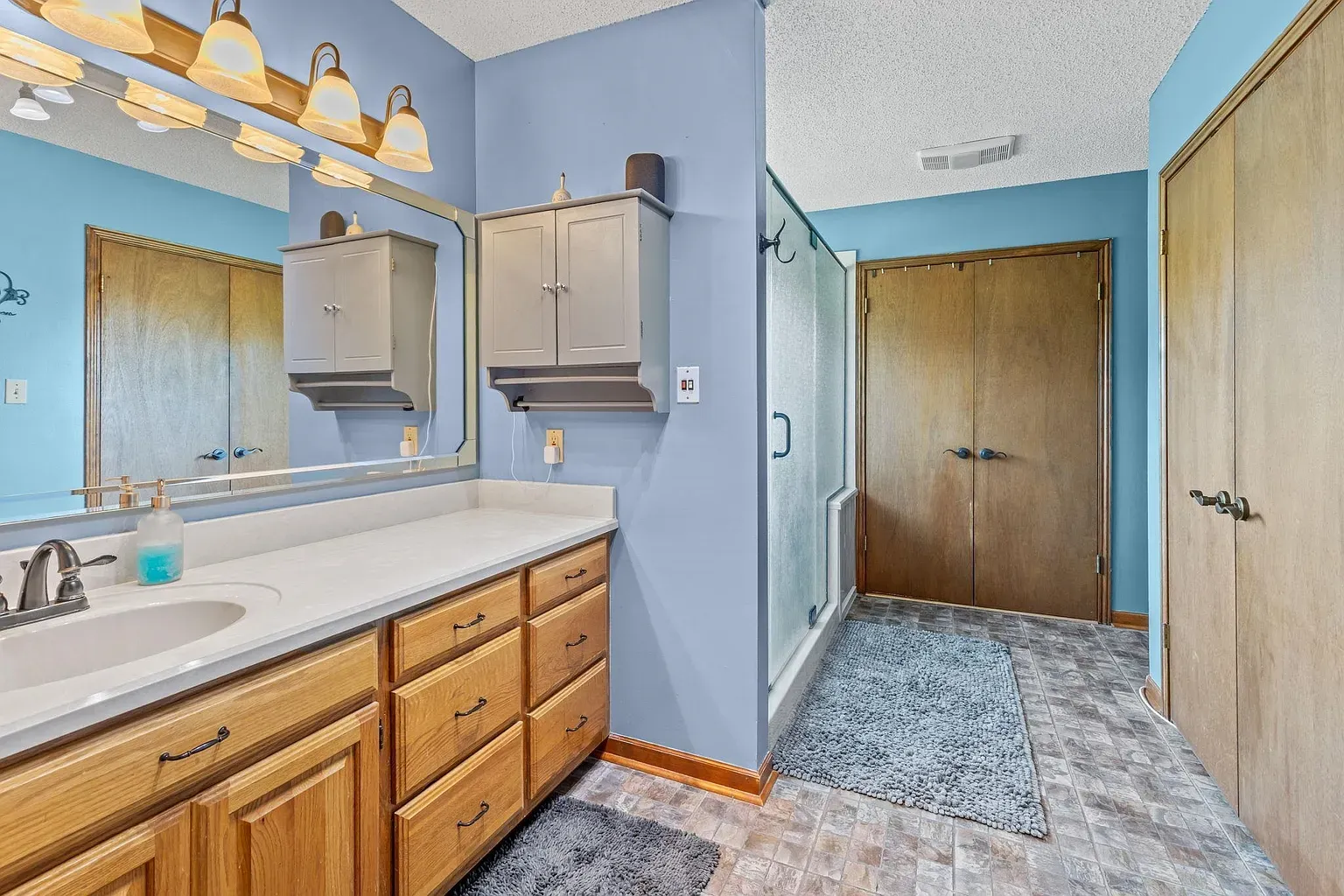 Second bath sticks to blue walls and oak cabinets. Lots of storage.