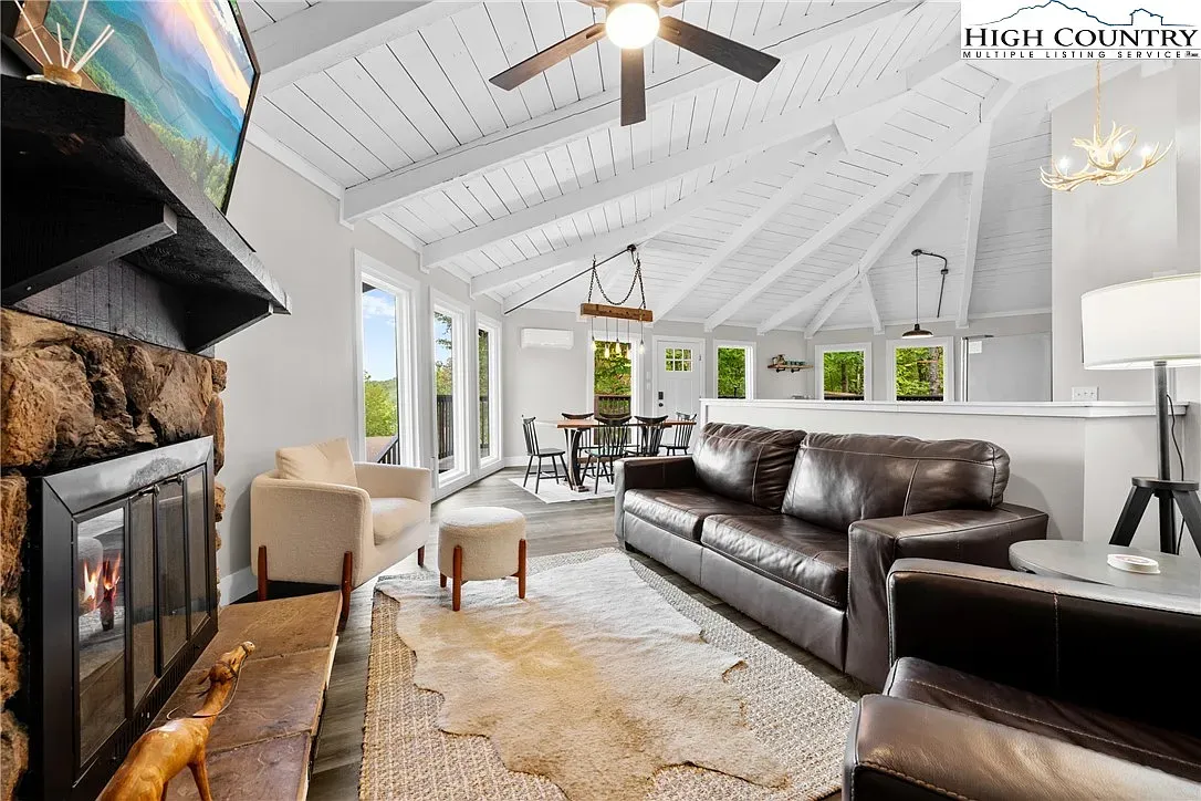 ## Airy living area ahead—vaulted ceilings, white beams, and sunlight pouring in from big windows.