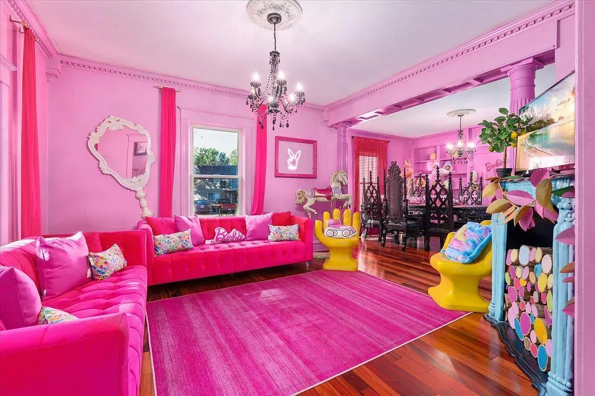 ## Bubblegum-pink lounge stretches out, detailed crown molding showing off the room’s bones; it reads social, bright, and ready for a big group.