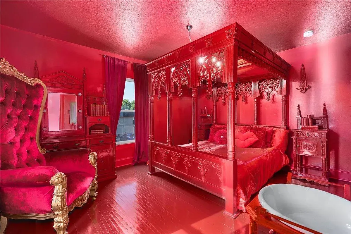 ## Crimson bedroom shifts the mood; an ornate Gothic-Victorian four-poster commands attention and gives the space a dramatic, luxe night-at-the-castle vibe.