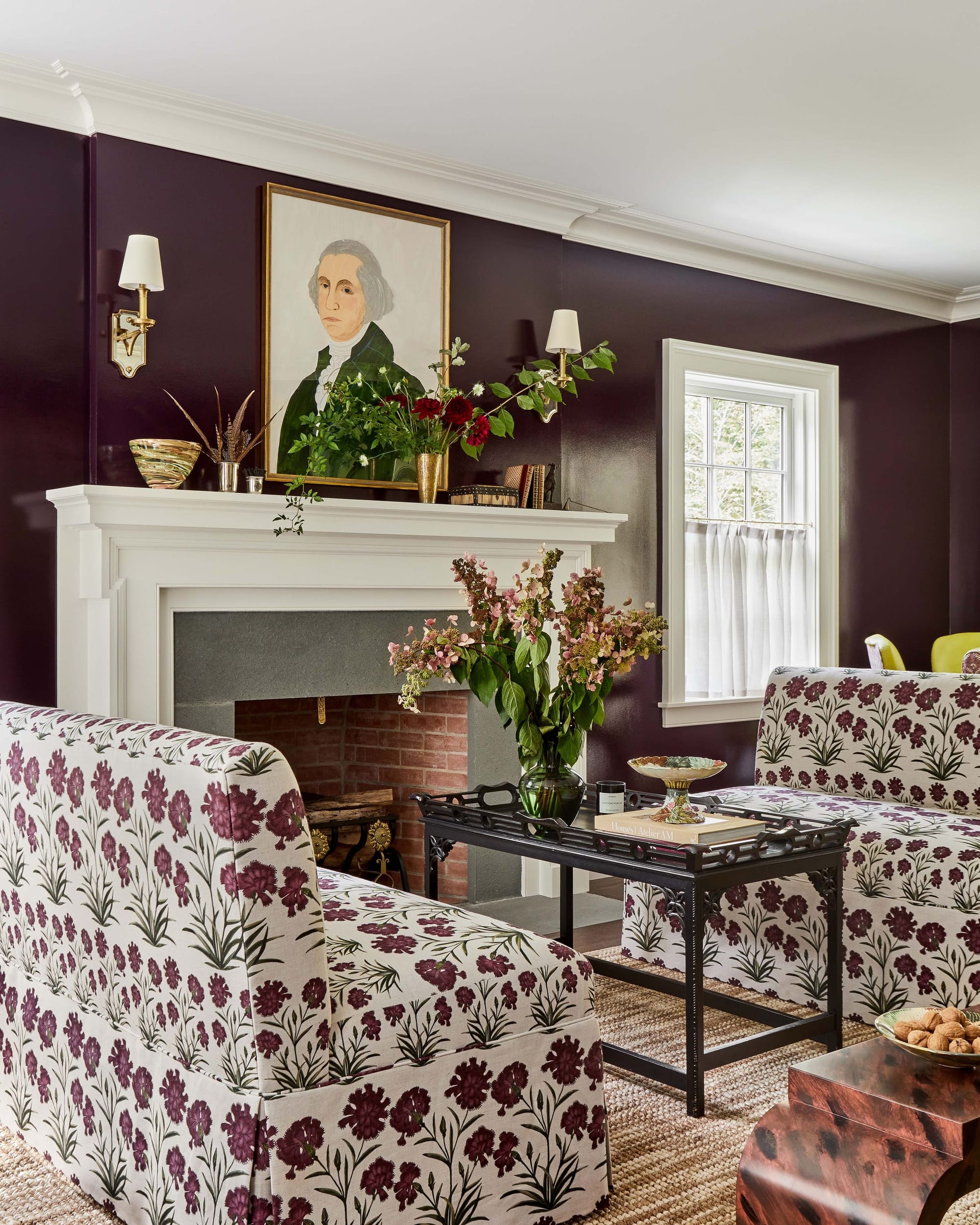 "A sophisticated living room where Colonial elegance meets modern comfort, anchored by deep plum walls and a historical portrait above a classic white fireplace!"