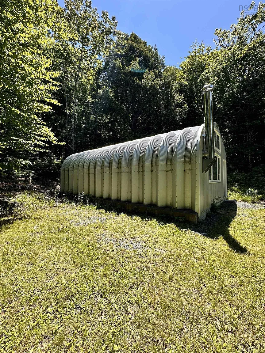 Okay, this one’s greener and rust-kissed. Vintage Quonset cosplay, blending into trees.