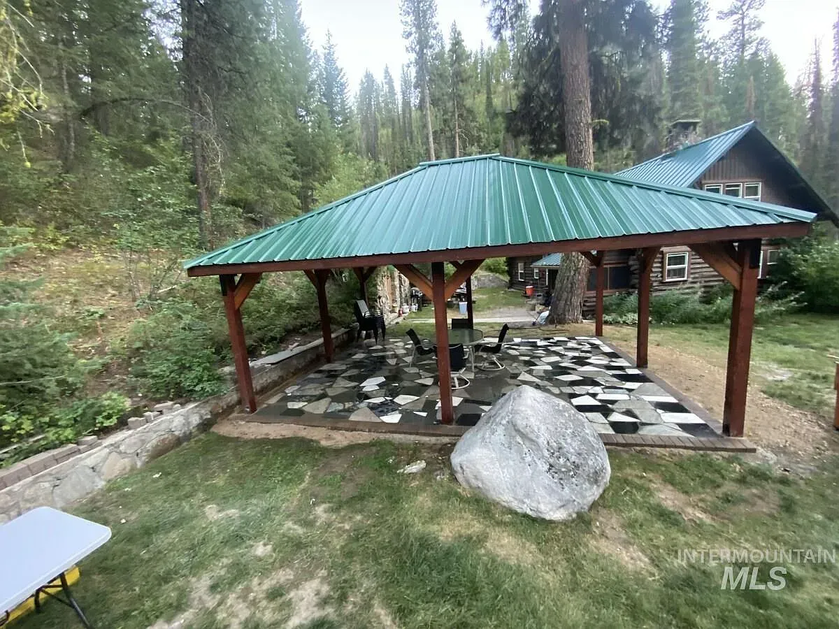 ## Green metal roof gleams overhead; dark beams anchor it, while an irregular stone mosaic underfoot feels artful and wild.