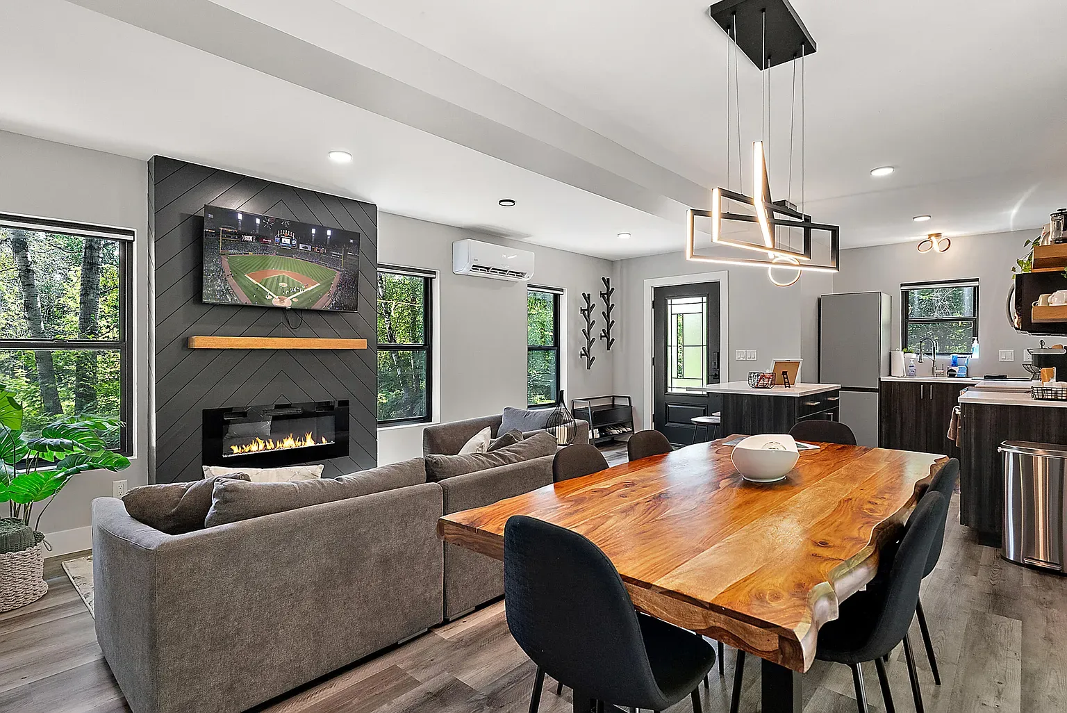 Open living room with that dark feature wall and linear fireplace. Cozy glow.
