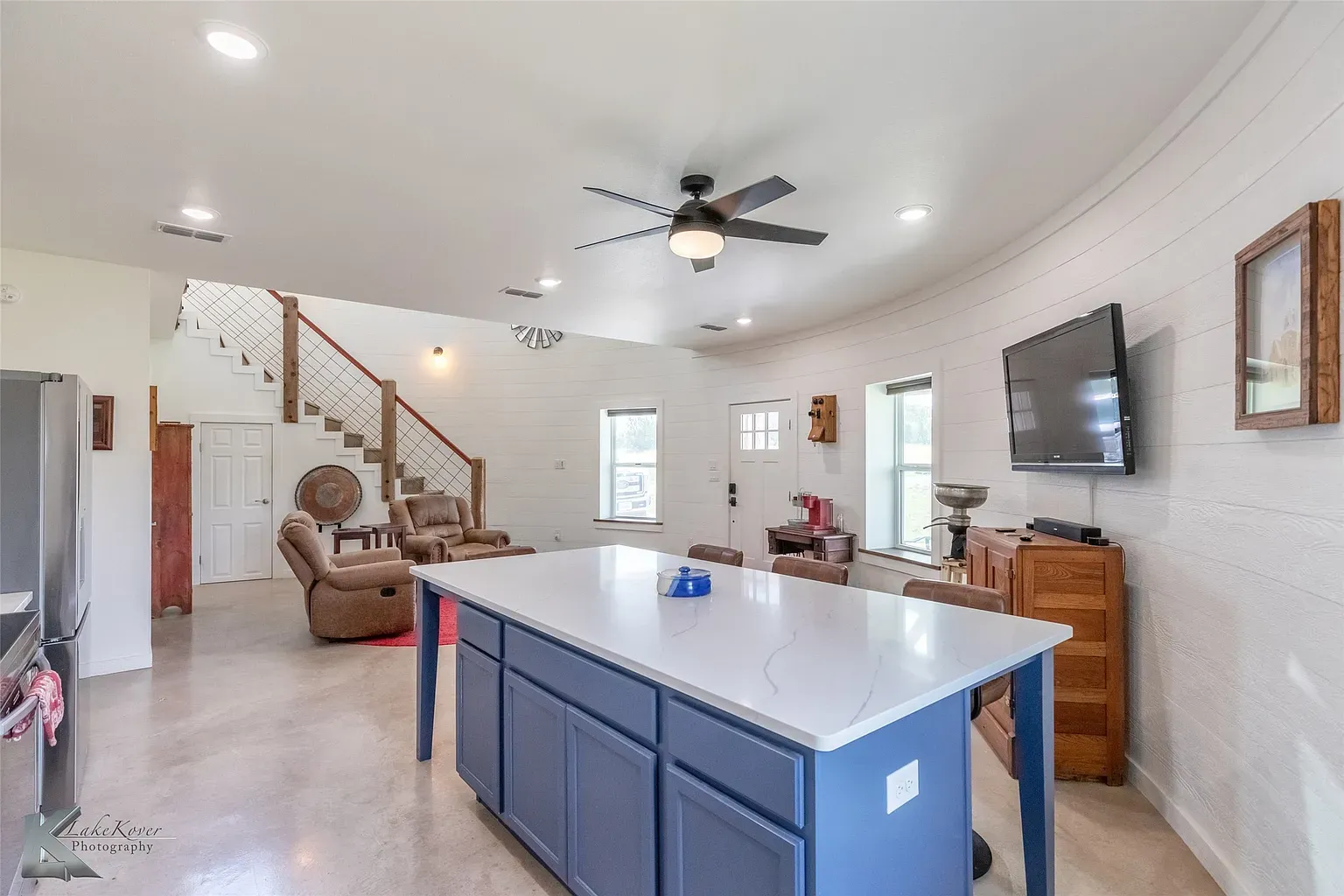 Here's the hangout—open living-kitchen. White island, navy cabinets, easy flow. Price tag nags me though.