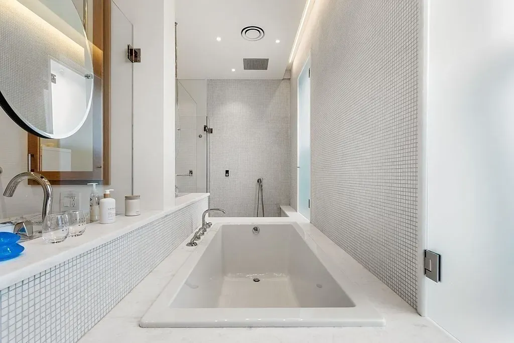 'Here's the bathroom, which has this nice deep tub and really practical tile work. It feels super clean and modern!’