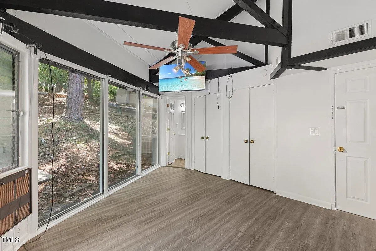 ## Sunroom number one feels airy: high vaulted ceiling with dark beams, glass all around, and light pouring in from every side