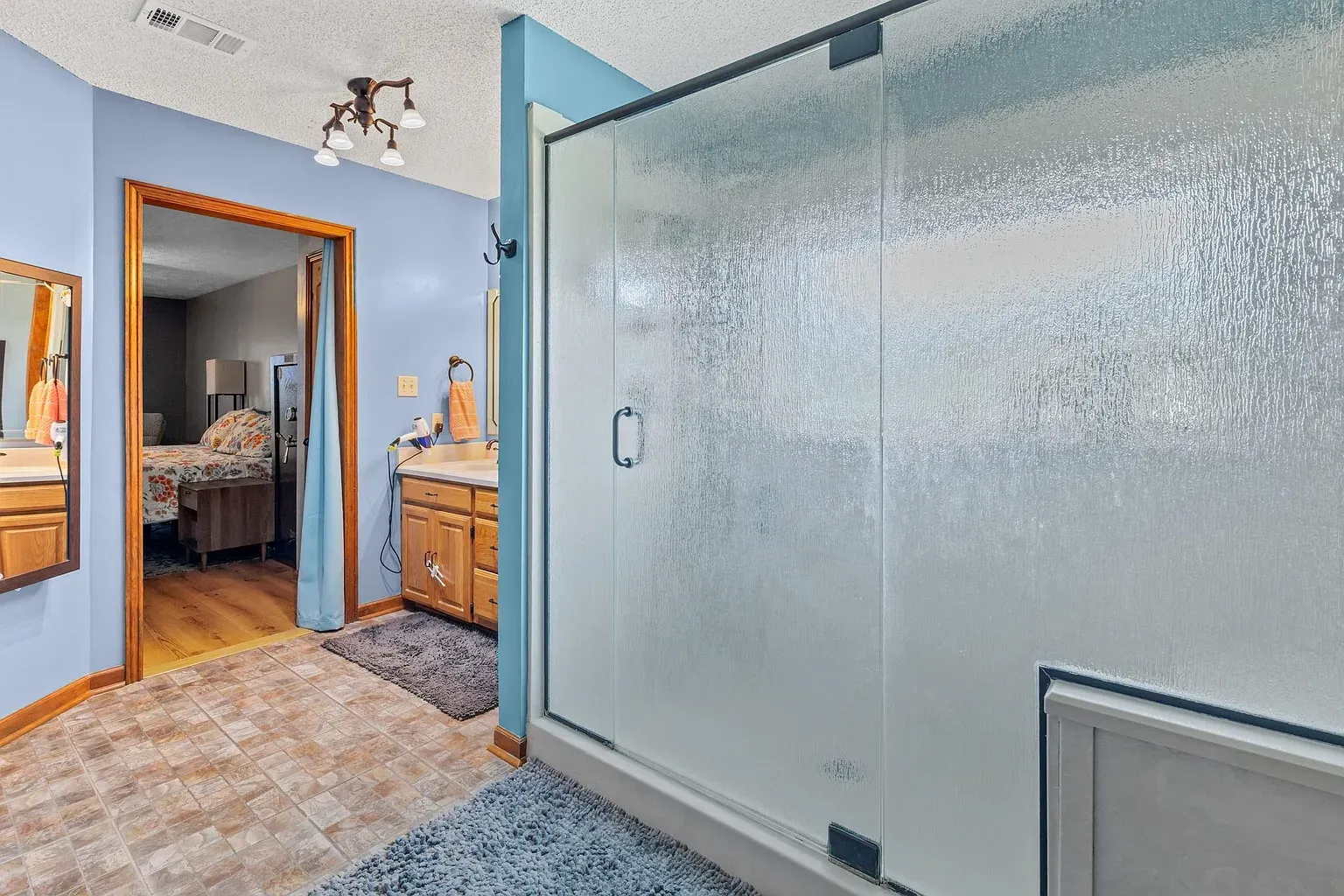 Bathroom one. soft blue, wood vanity, nice mirror. Simple spa vibe.