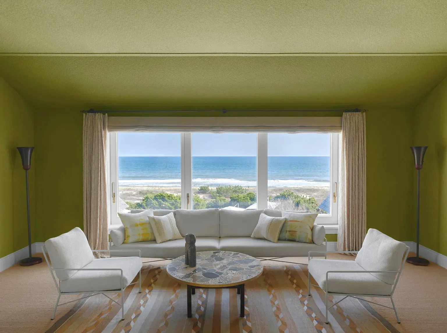 "Can you believe this view? The ocean is just right there! And I love how the bright green walls make the space feel so vibrant and cheerful. It's the perfect spot to relax and take it all in!"