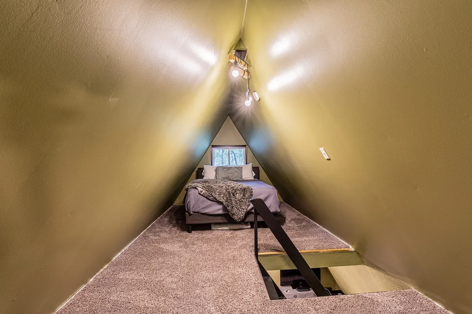 Inside the A-frame. olive walls, tiny window glow. Cozy triangle energy.