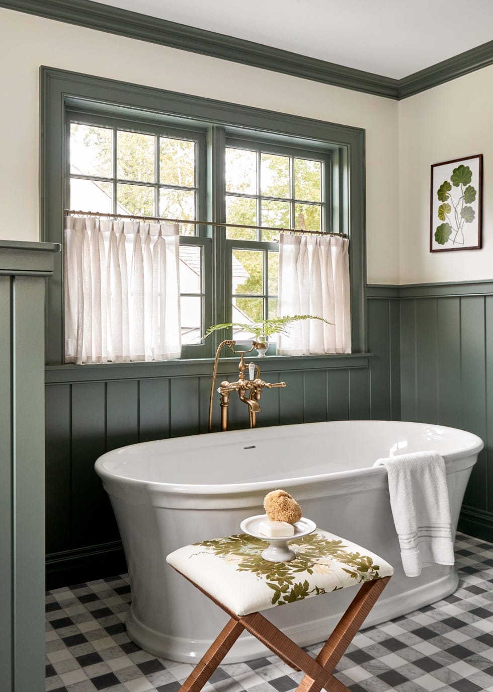 "Soak in luxury in this elegantly designed bathroom featuring a classic freestanding tub, sage green wainscoting, and charming brass fixtures that create a serene retreat!"
