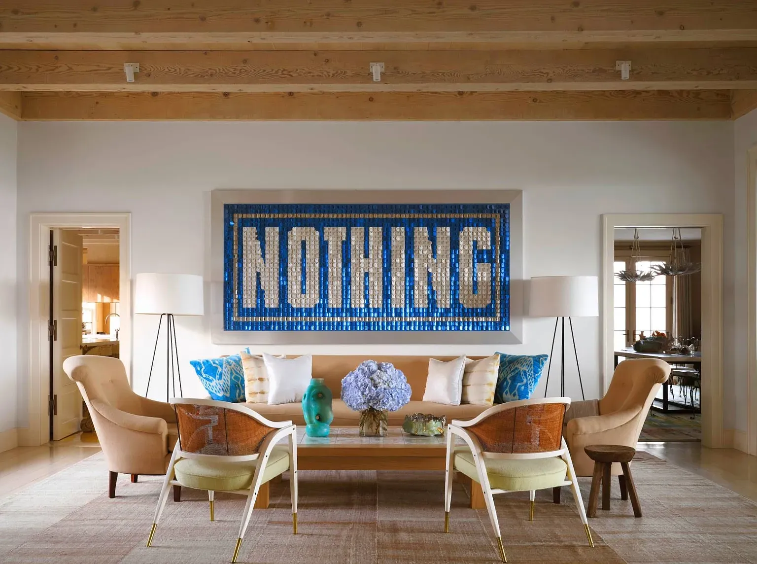 "Oh, this living room has such a cool vibe! Look at that bold artwork—it really makes a statement. The beams give it a nice airy feel, and those comfy chairs are perfect for relaxing with a book. Plus, I love how the colors