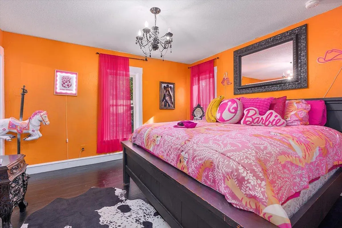 ## Bright orange walls meet deep pink drapes; sunlight filters through sheers and the whole bedroom feels upbeat and ready for a fun morning.