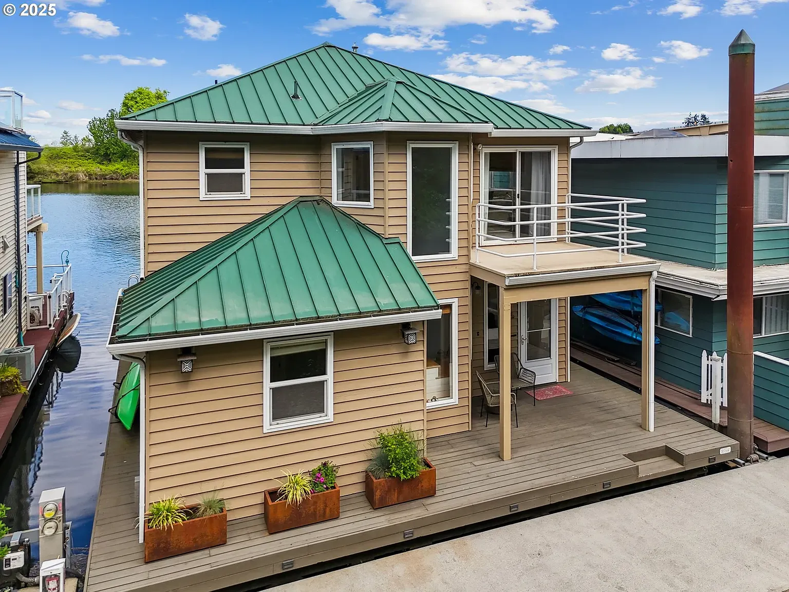 Here's the floating home — sandy siding, green metal roof. Cute and modern.