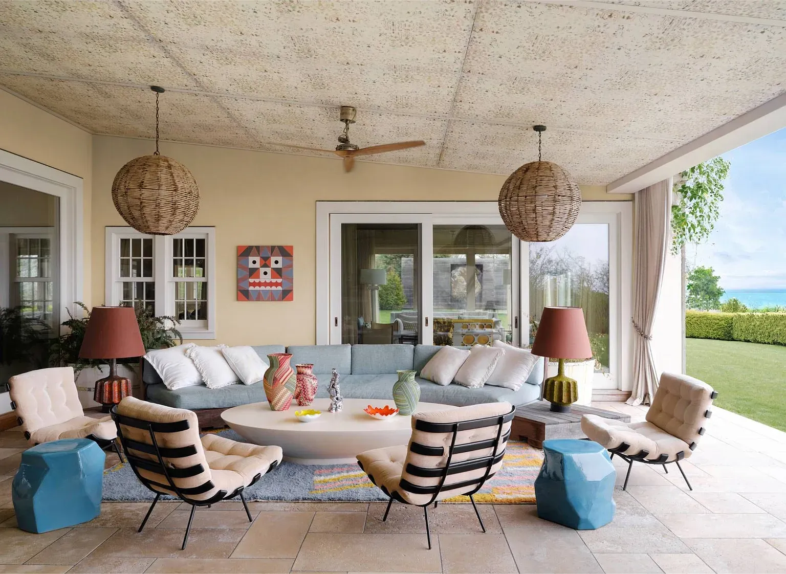 “Come hang out in this relaxed outdoor lounge! I love how the big sliding doors open up to the lush backyard, and those colorful chairs and lamps just bring the space to life. Perfect for enjoying a drink with friends!”