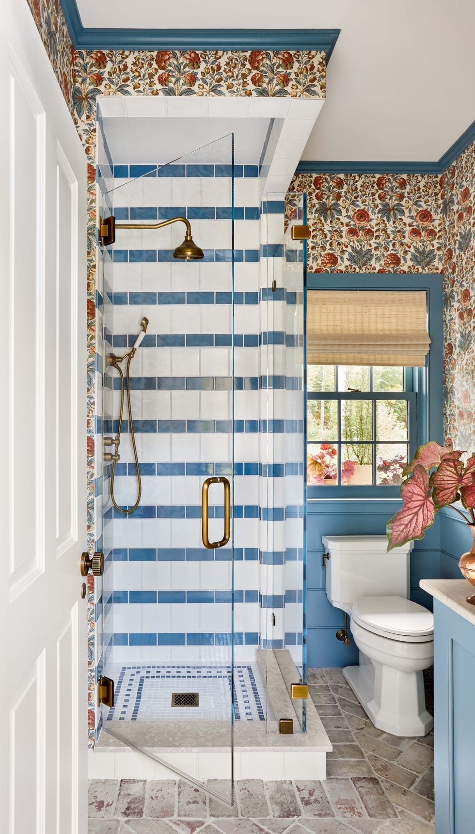 "Step into this charming bathroom where vintage floral wallpaper meets modern blue accents, creating a timeless retreat with brass fixtures and a luxurious glass shower!"