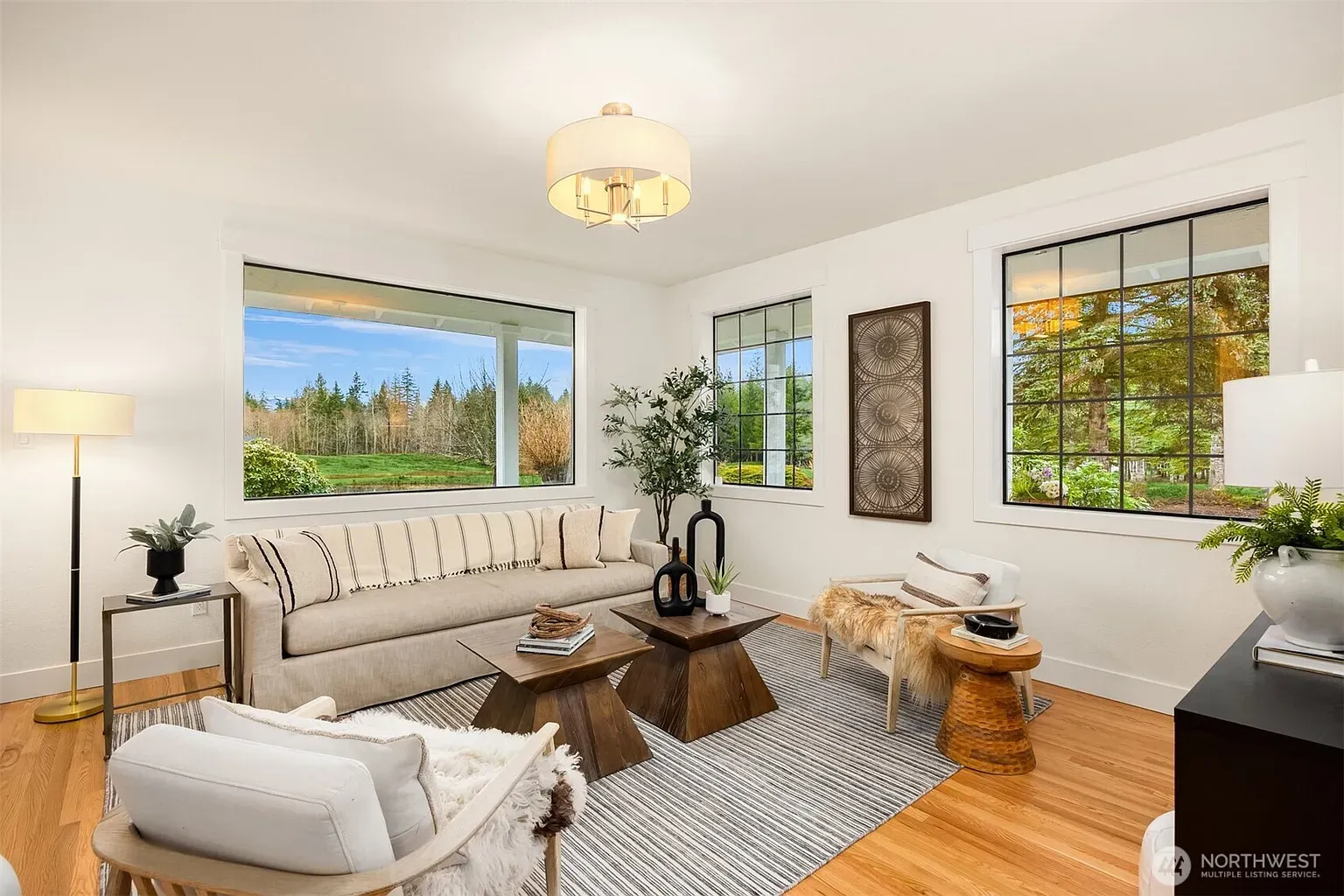 Bright living room, huge windows, greenery everywhere. Sofa looks dangerously nap-friendly.