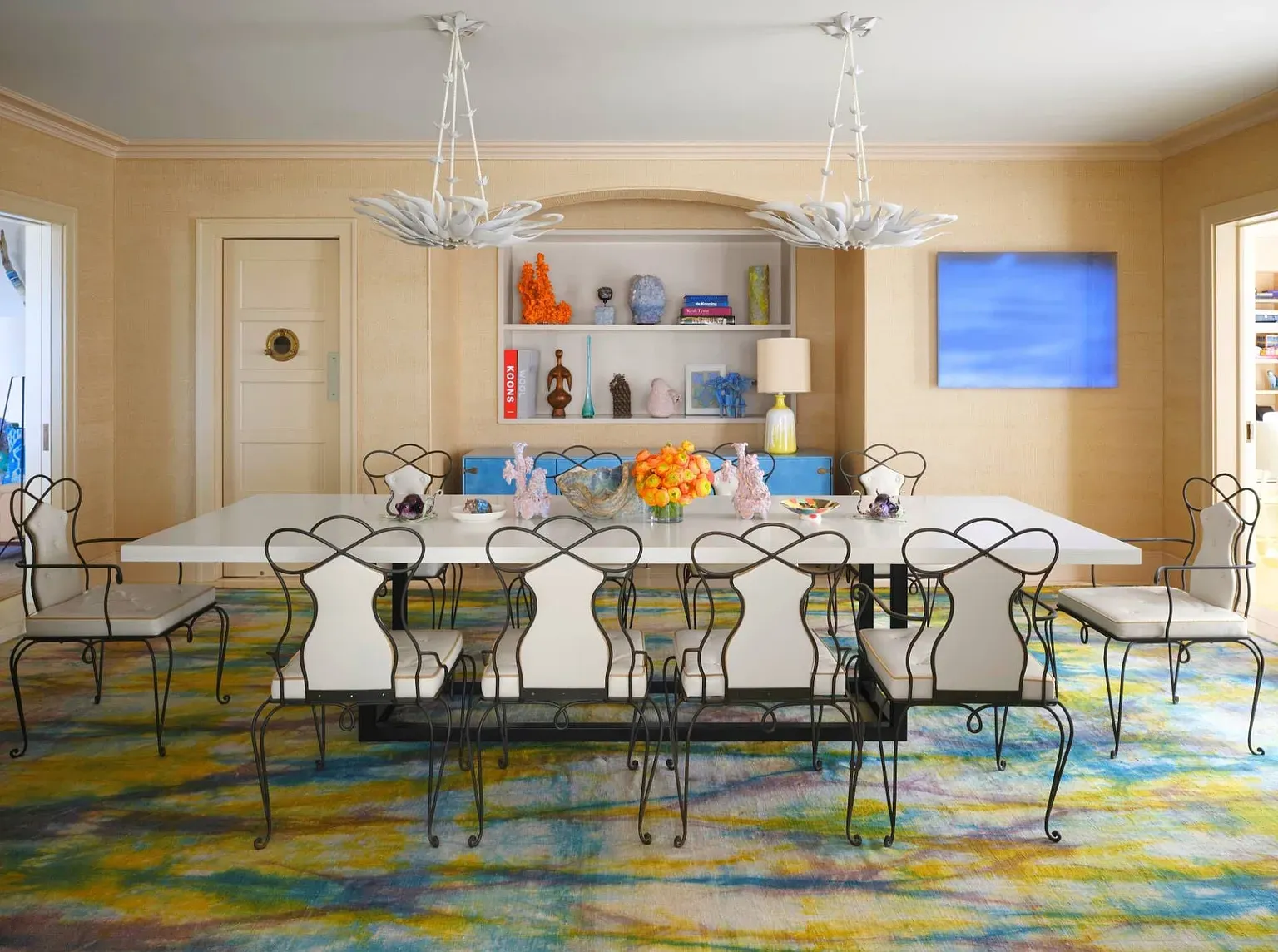 "Here’s the dining room — it’s got this long table that can fit a big crowd for dinner. I love the unique chairs and those light fixtures up top. The colors on the rug really brighten up the space too!"