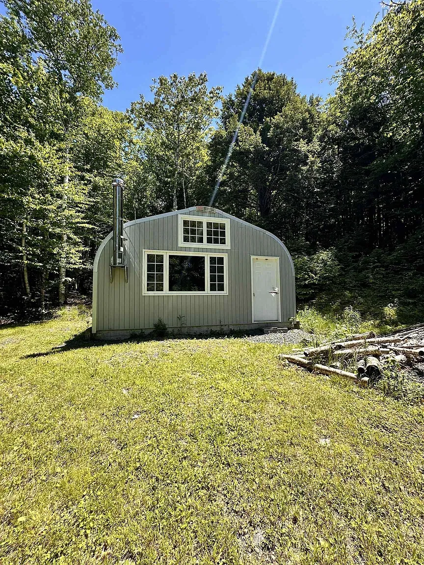 Another angle — sleek curve, soft silver siding, huge window strip. Forest looks happy.