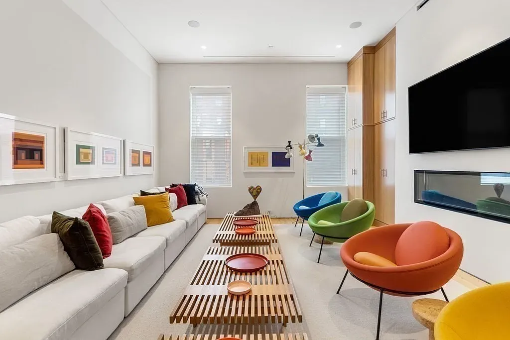 "Here’s a really inviting little lounge area with this super comfy sectional sofa and colorful chairs that just pop. The artwork on the walls adds so much character, and that sleek fireplace is perfect for cozy evenings!"