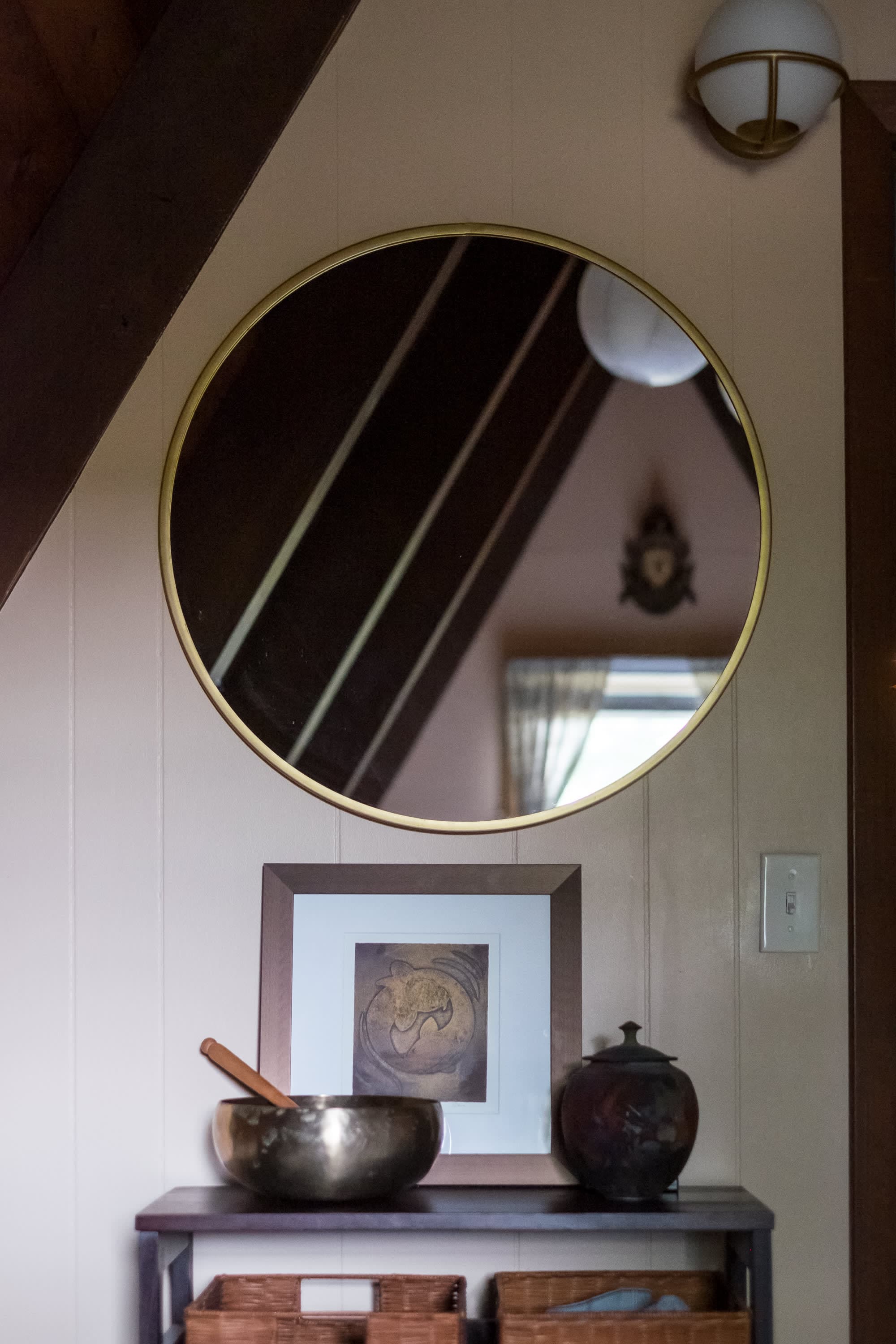 "Zen-inspired entryway with singing bowl and stylish round mirror!"