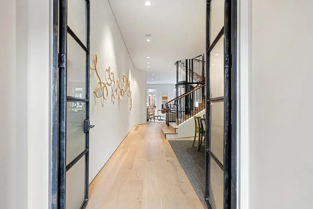 "Take a look at this welcoming entryway! The open layout really lets in the light, and I love how those glass doors give it a modern touch. Plus, the staircase with that sleek railing is just so inviting!"
