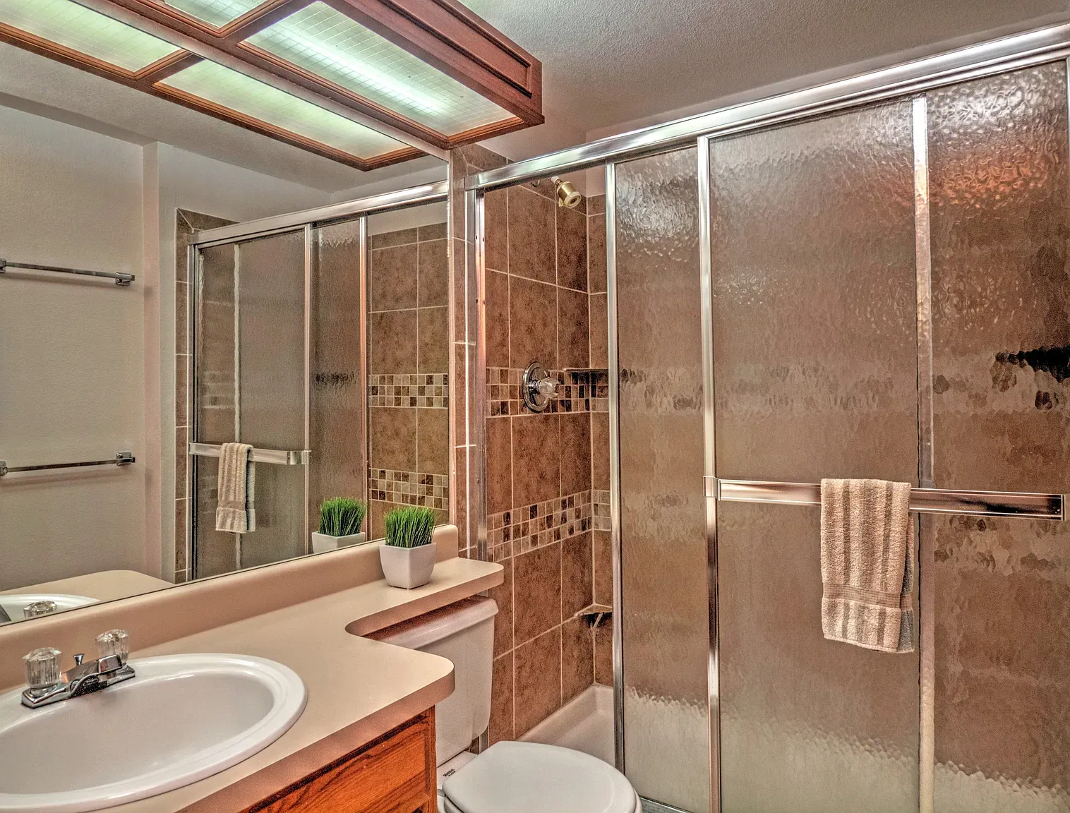 Clean bathroom vibe. frosted glass shower, warm tiles, simple hardware. Looks easy.