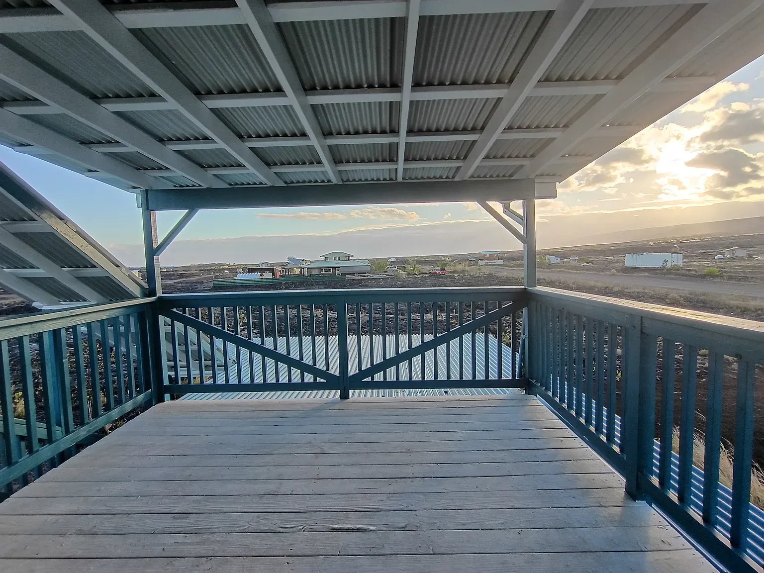 Elevated deck, weathered boards, teal railings. Looks breezy, perfect for mornings.
