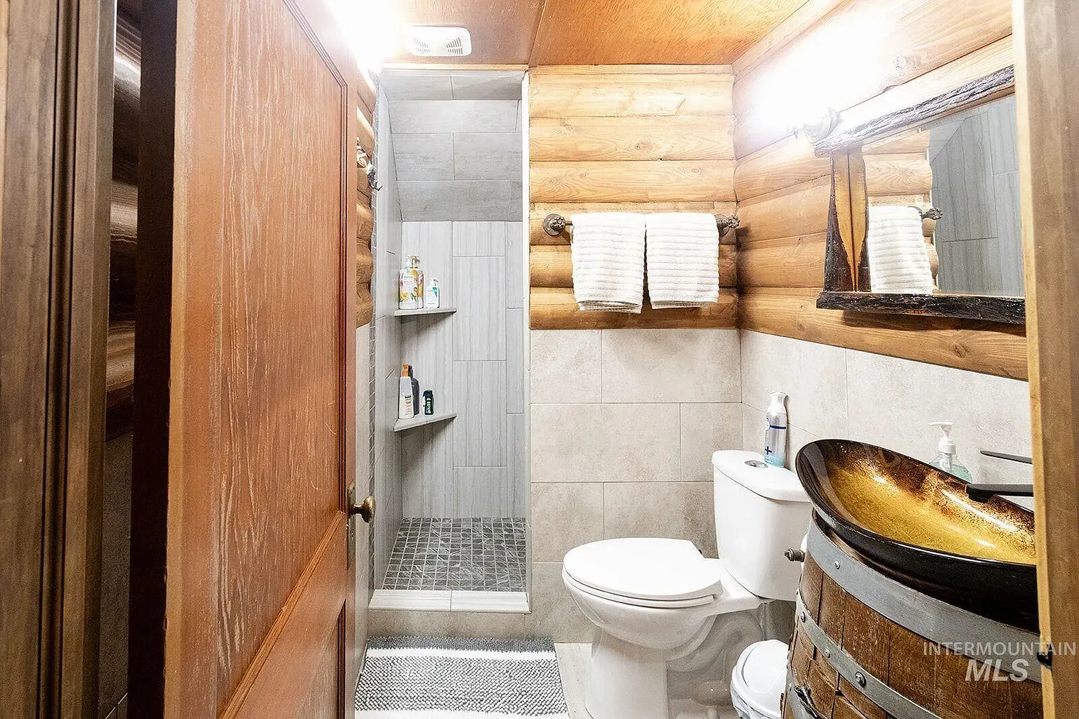 ## Warm log walls wrap the space; elegant stone tiles underfoot add a grounded, polished note.
