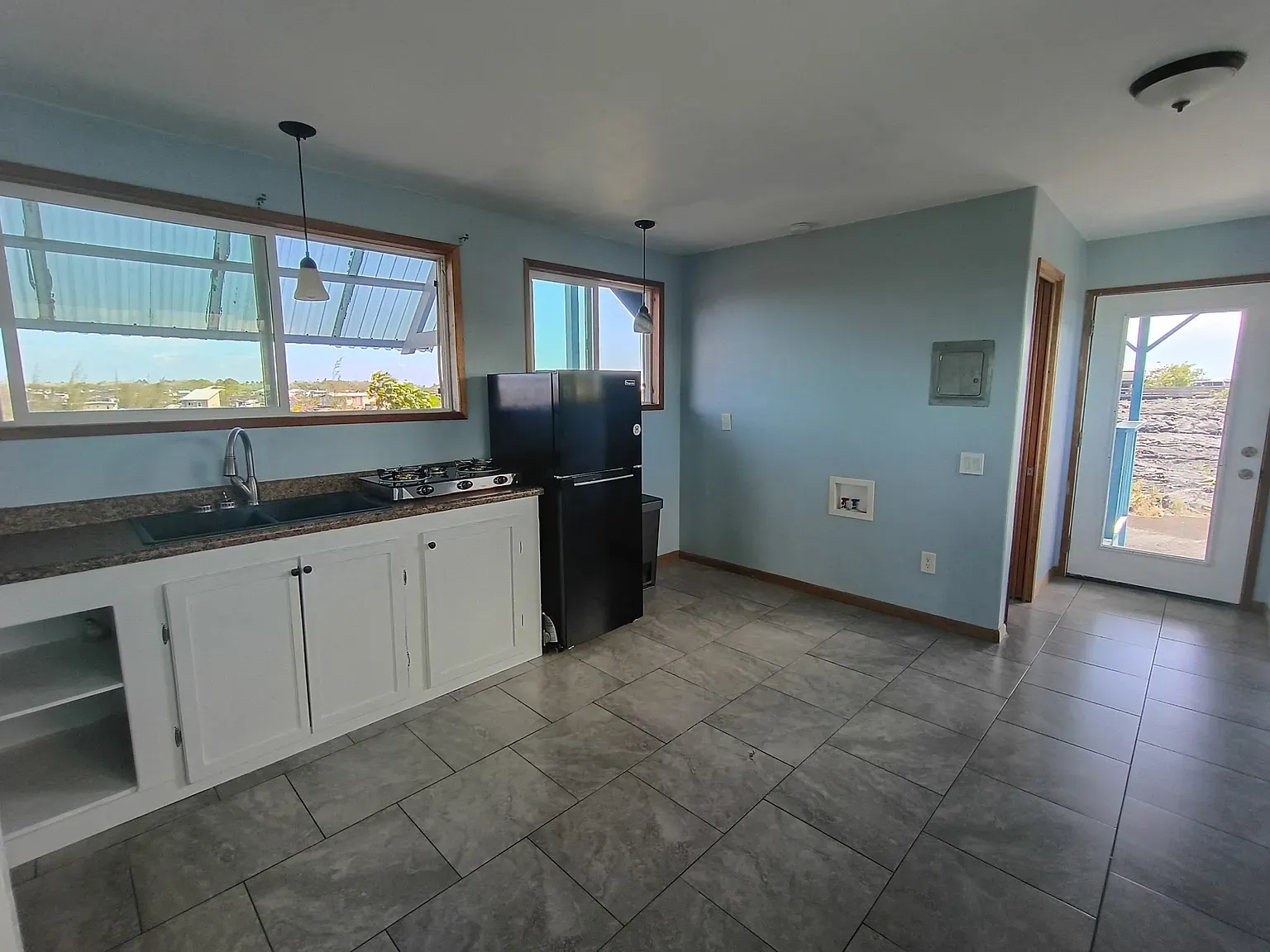 Second kitchen angle — pale blue, white cabinets, windows doing all the work.