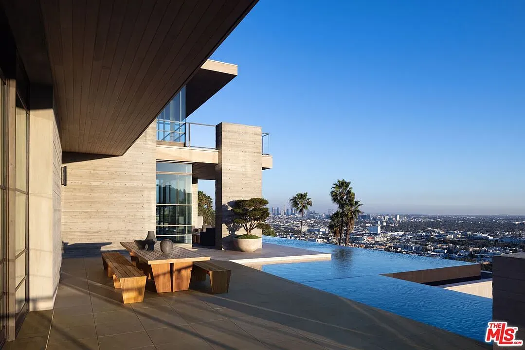 Here's the outdoor hang — glass walls, huge skyline view, blue-sky flex.