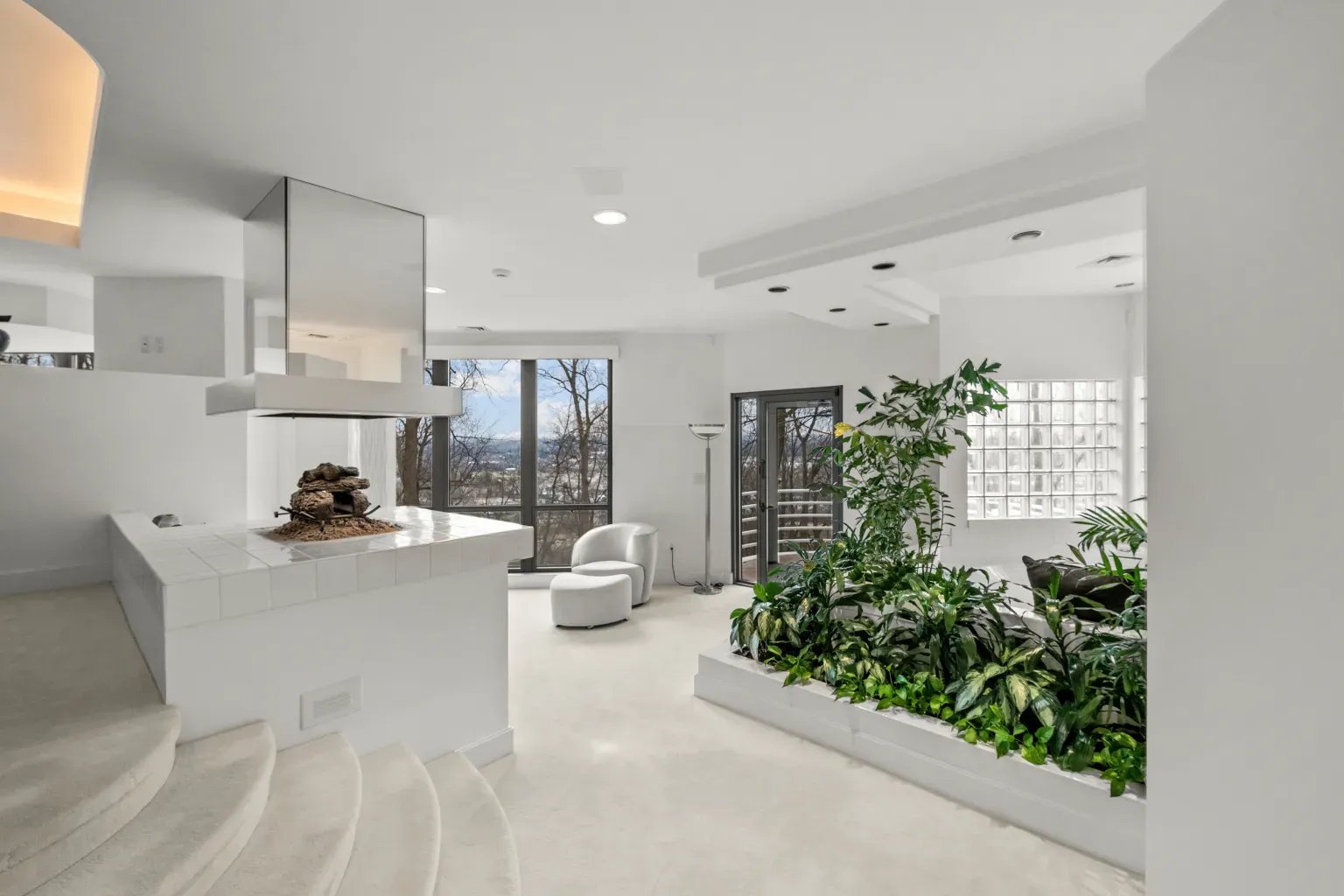 Open living room, soft whites and beige. Big plant moment stealing the scene.