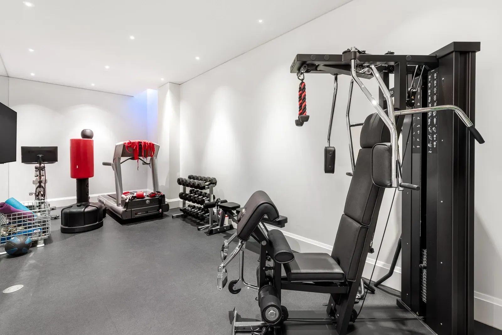 Back to basics gym—black rubber floor, white walls, mirrors for days.