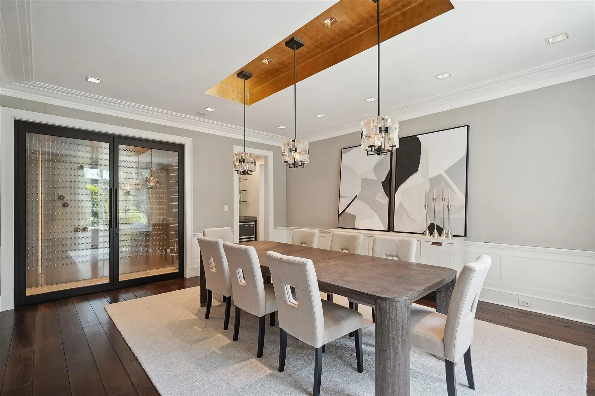 Dining setup is clean. Big wood table, soft chairs. What’s above—sculptural light?