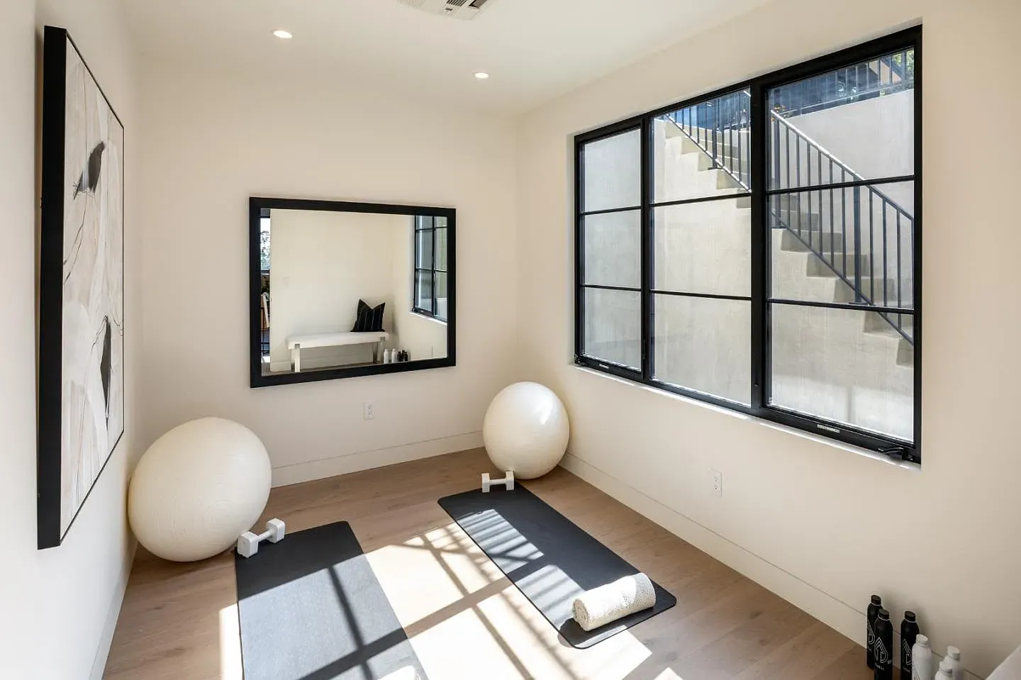 Bright home gym with black windows and beige walls. Peaceful but functional.