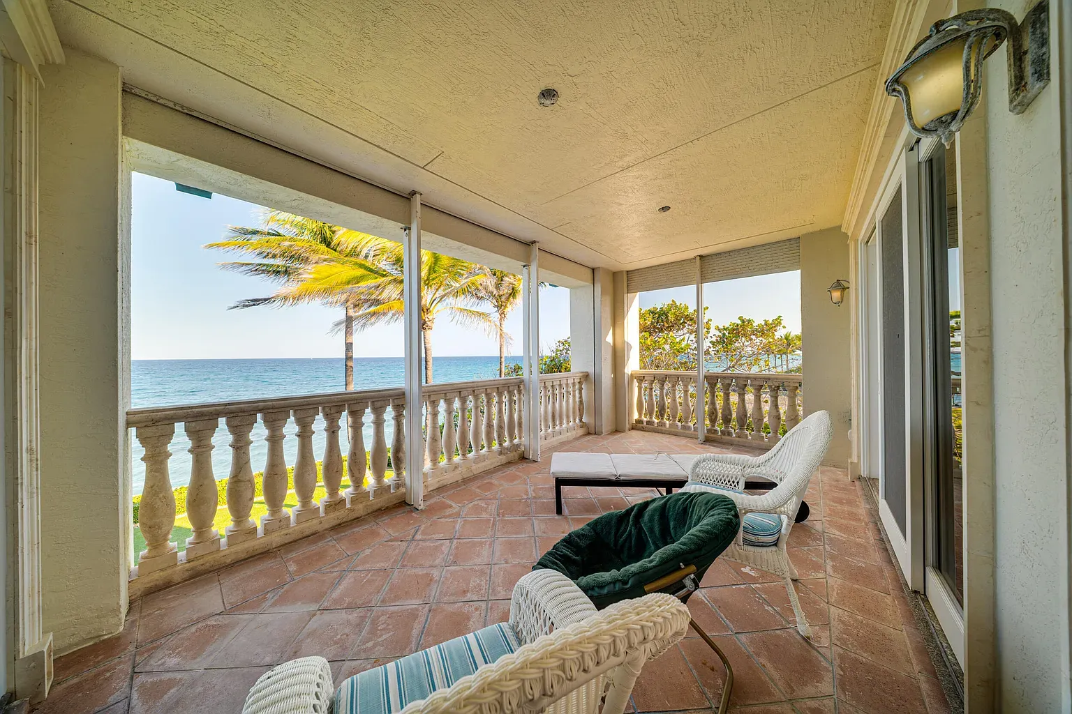 Sunroom balcony with terracotta floors. Windows everywhere, just swallowing that coastline.