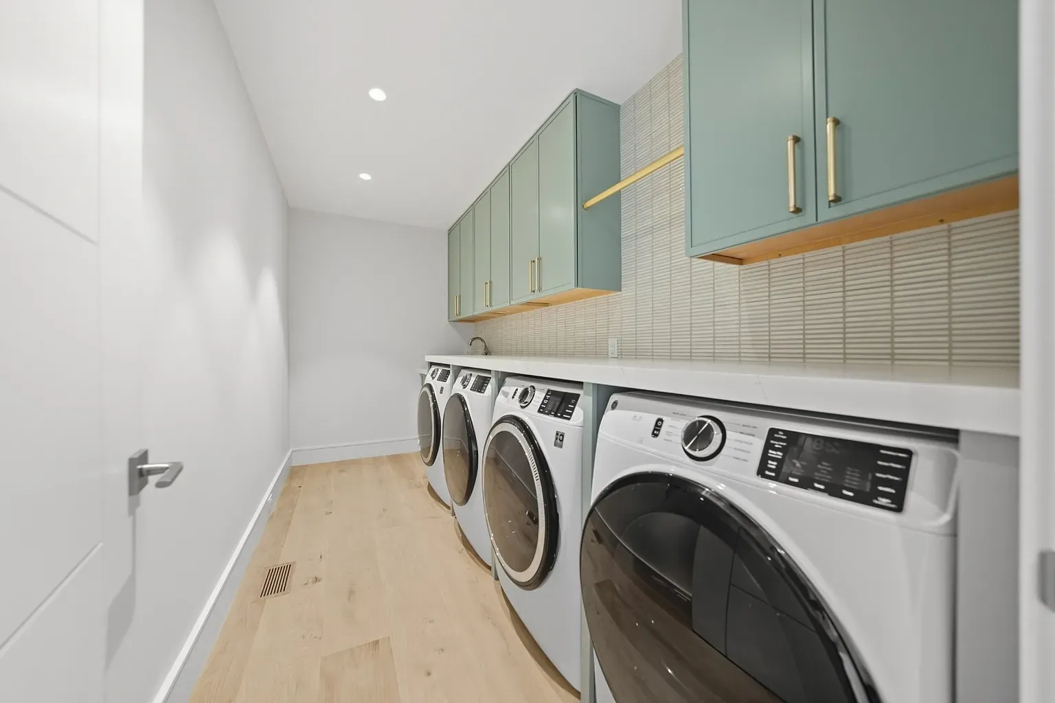 Laundry zone looks nicer than my kitchen. Stacked machines, clean cabinets.