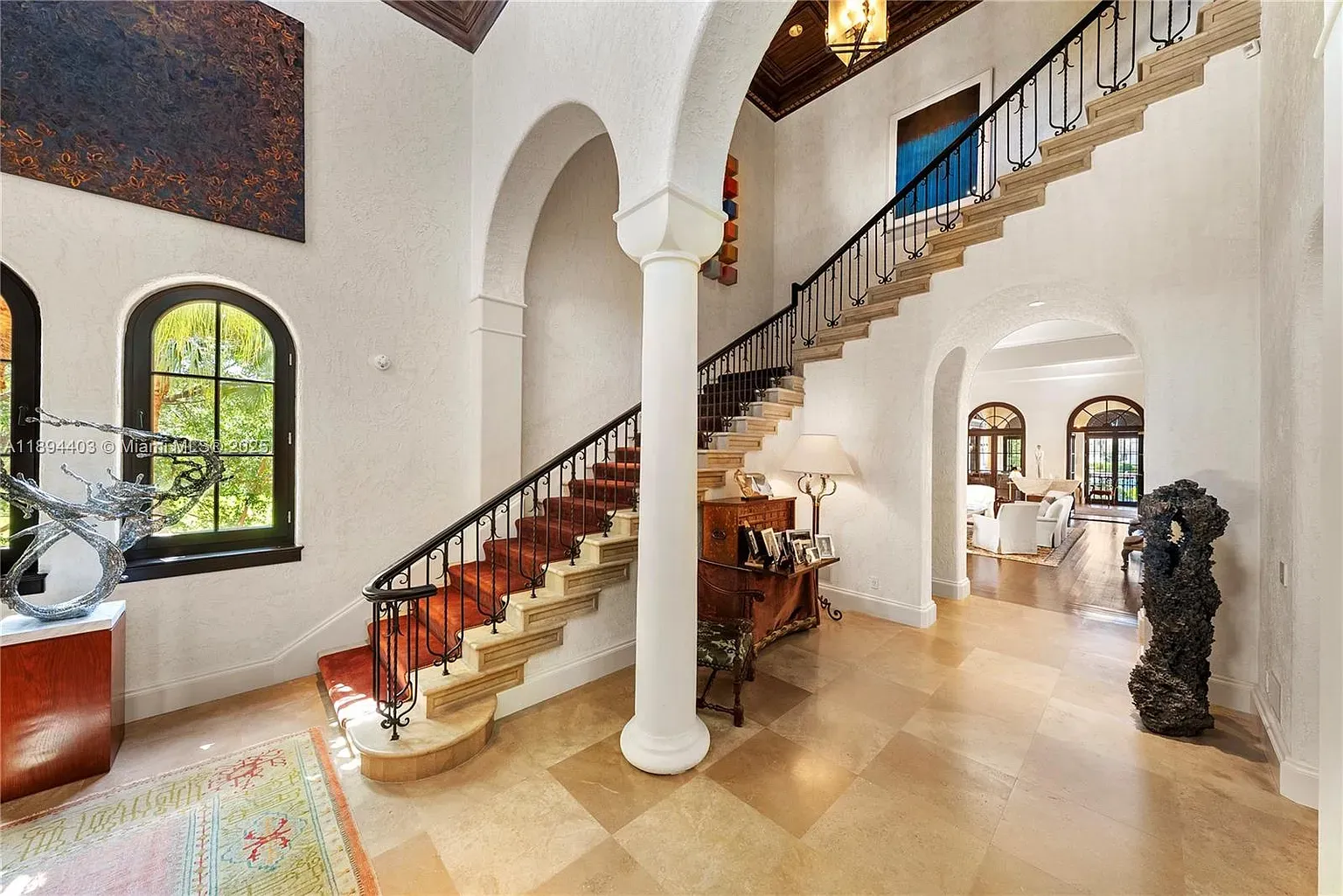 Here's the foyer—soaring ceilings, wood rail, creamy travertine. Big first impression.