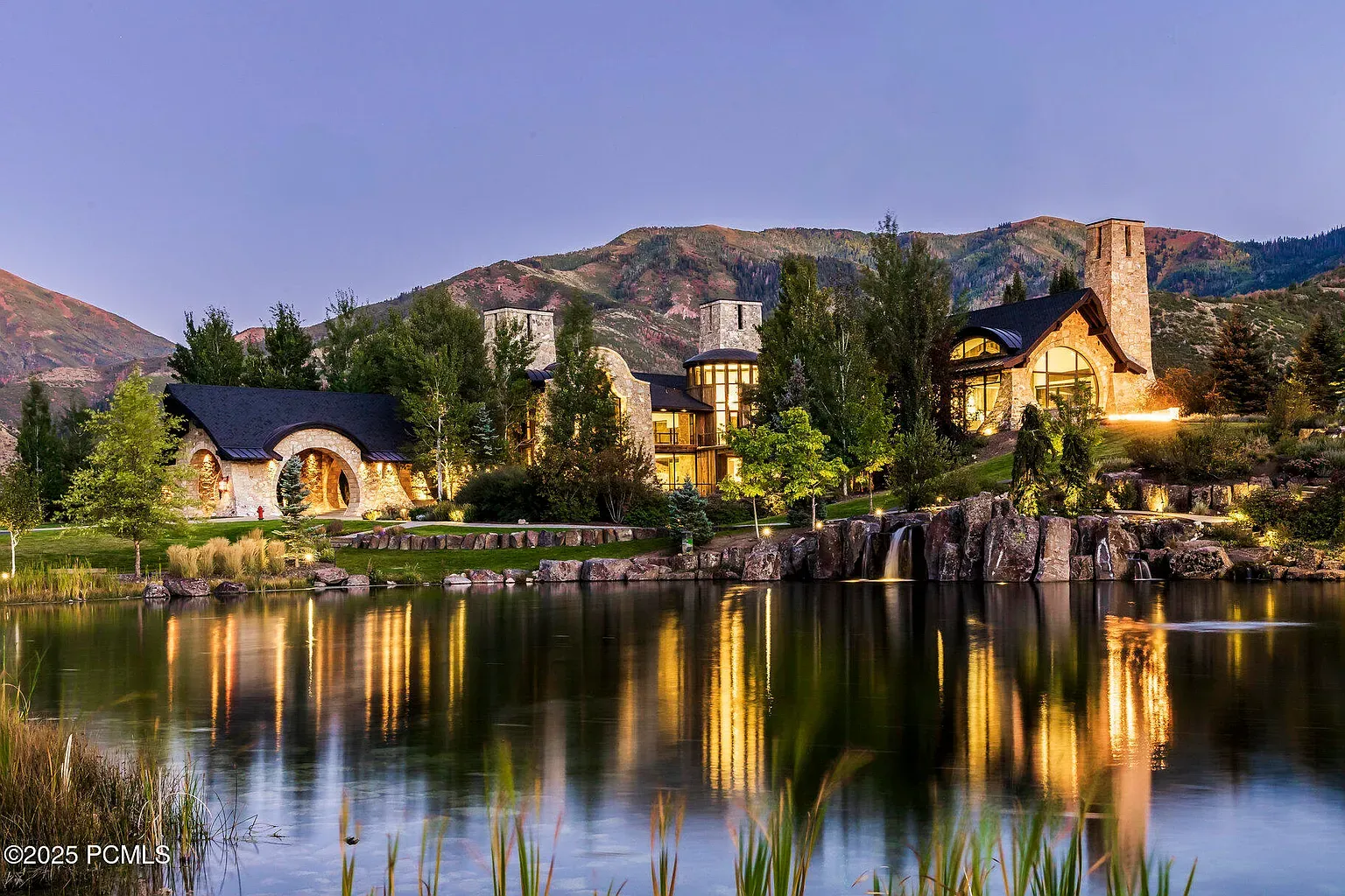 From across the lake, the house glows. Stone, wood, glass playing nice.