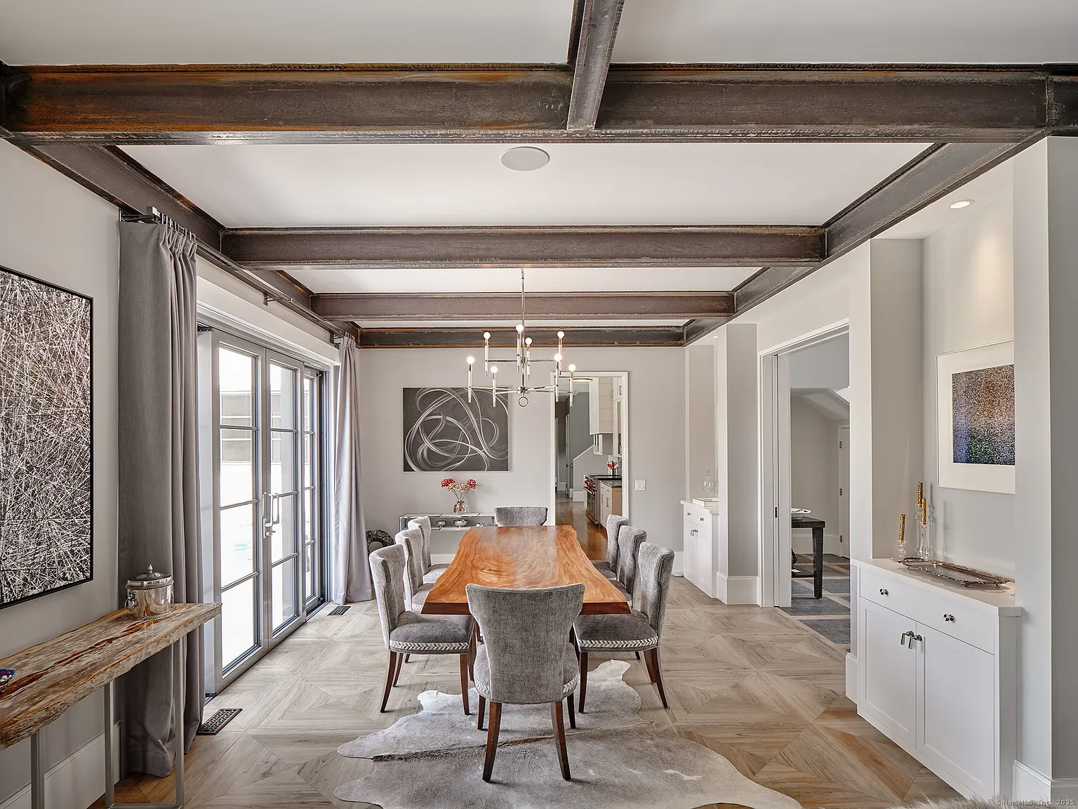 Long wood table, squishy gray chairs, simple ceiling. Cozy without trying hard.
