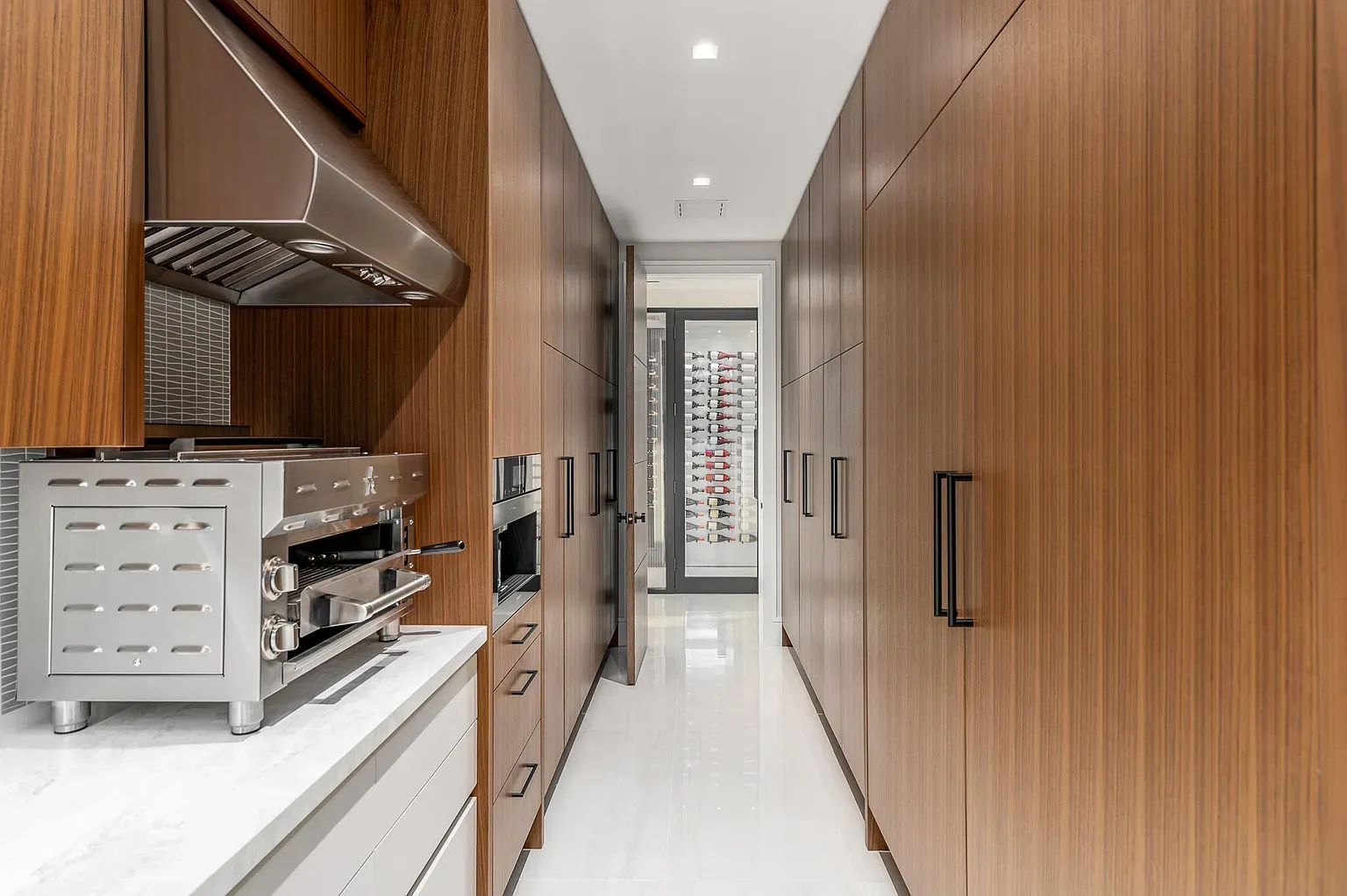 Hallway kitchen with wood wraps and glossy marble floors. Slip-n-slide or chic?
