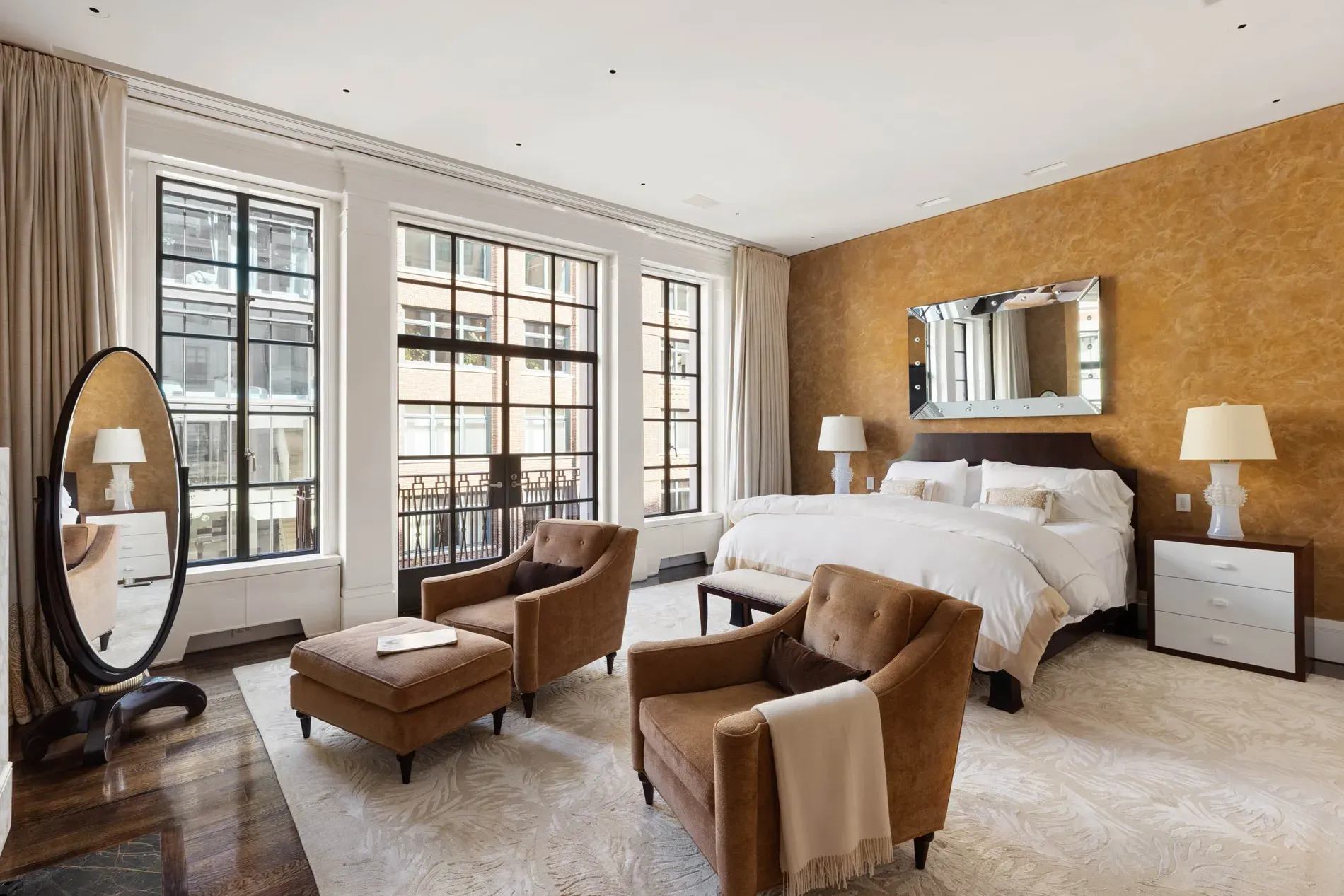 Golden accent wall behind a cloud of white bedding. Cozy-luxe.