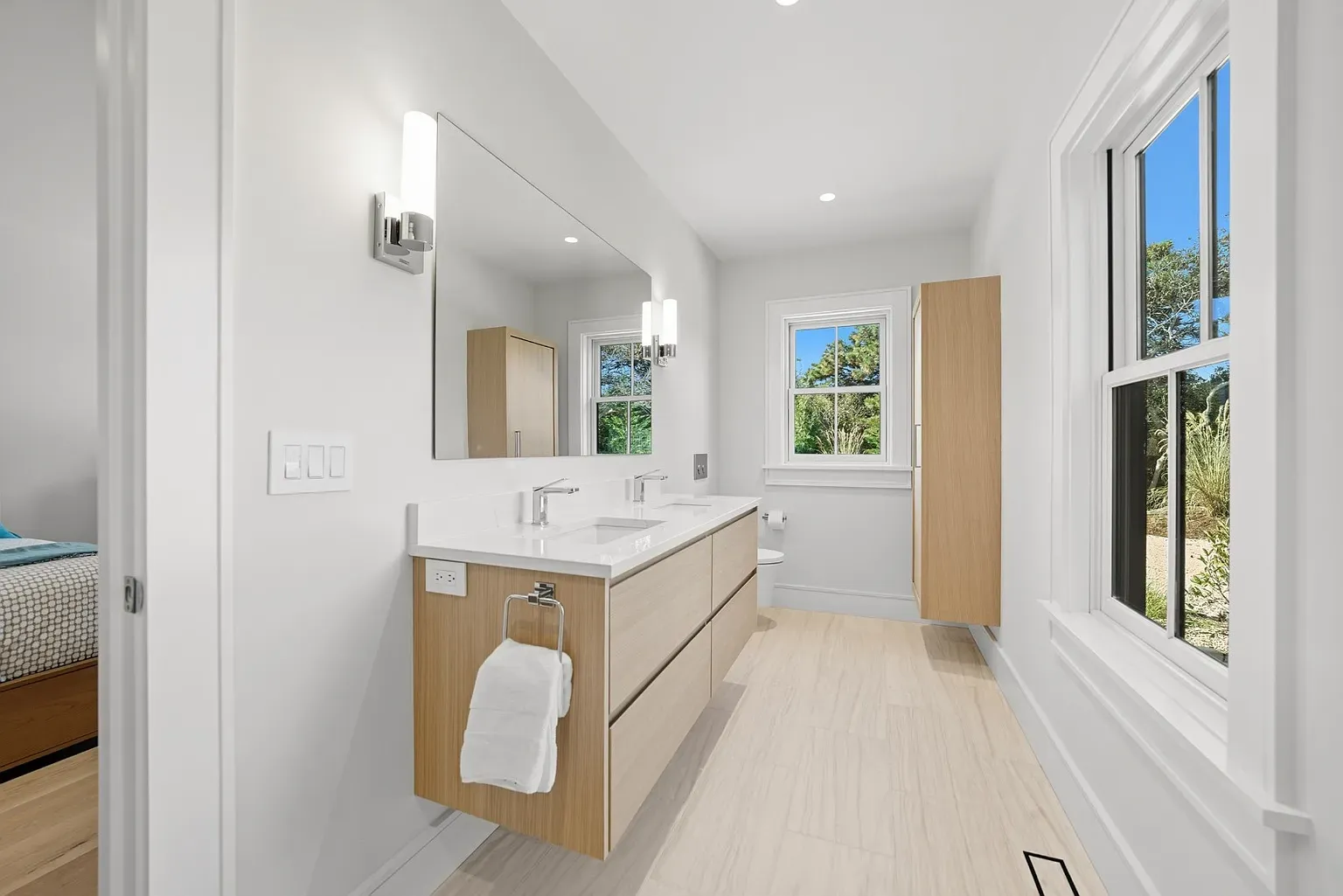 Double vanity with warm wood. Mirror basically the whole wall.