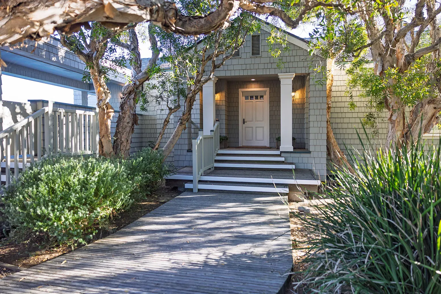 Front entry tucked into gray shingles and white trim. Feels tucked into nature.