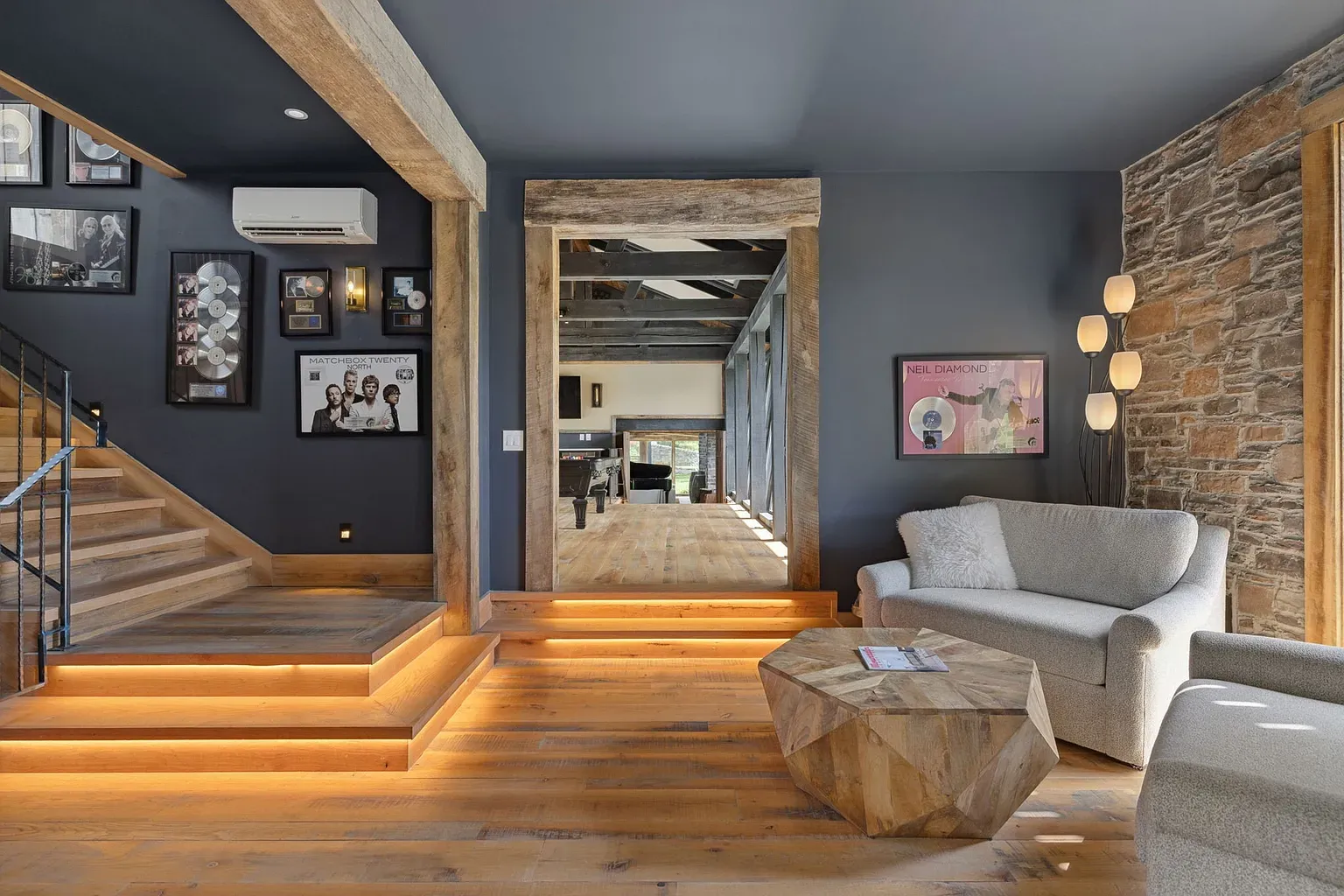 Charcoal walls, warm floors, and that wood-and-black staircase is doing the most.